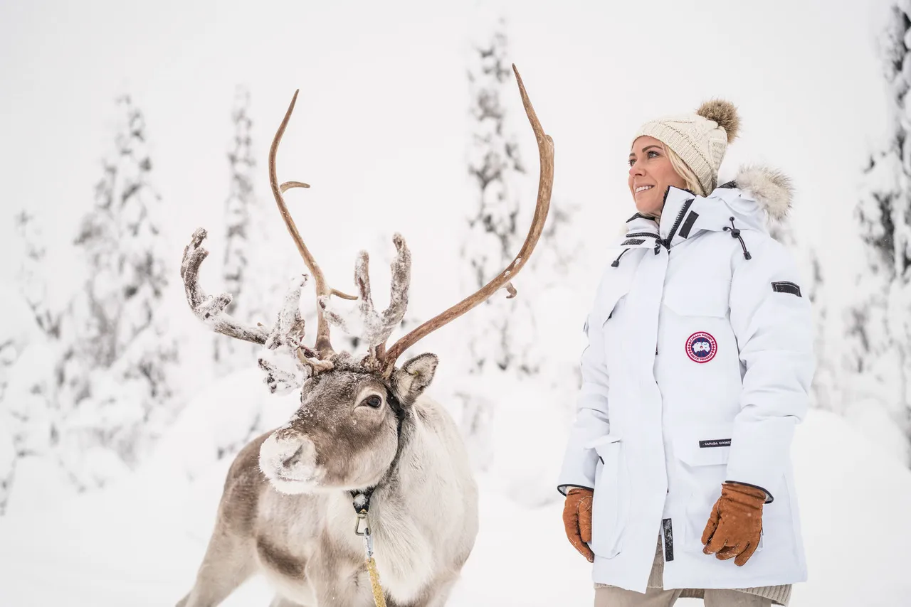 A visitor with a reindeer in a snowy forest near Levi